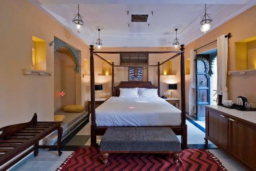a bedroom with a four poster bed and a bench at Gogunda Palace in Udaipur