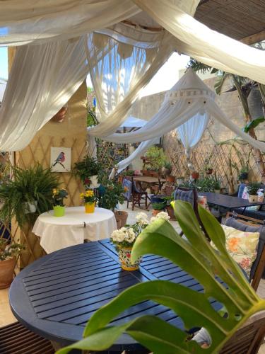 a patio with a table with white drapes at Botanica B&B in Xagħra