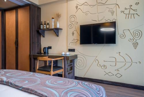 Zimmer mit einem Bett, einem Schreibtisch und einem TV in der Unterkunft Giuaani Winery in Manavi