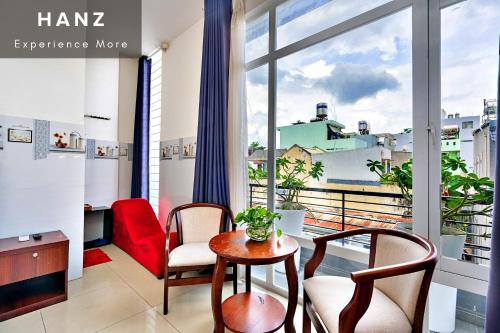 um quarto com uma mesa e cadeiras e uma grande janela em HANZ Phuong Thuy Hotel em Ho Chi Minh
