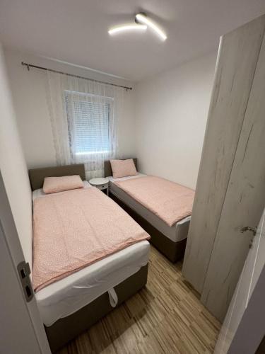 twee bedden in een kleine kamer met een raam bij Apartman Afrodita in Bosanska Gradiška