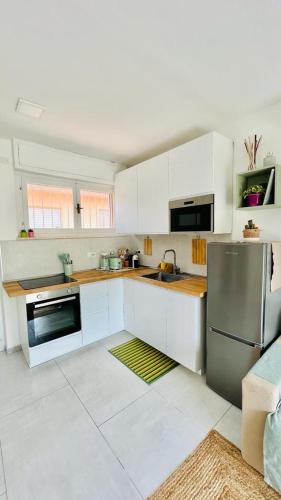 a kitchen with white cabinets and a stainless steel refrigerator at Silvy's Sunny House in Platamona