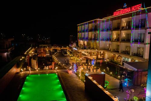 錫陀塔那迦的住宿－Asian Buddha Hotel，享有大楼的夜间景致,设有绿色泳池