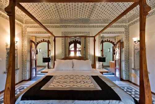 a bedroom with a large bed with an ornate ceiling at Gogunda Palace in Udaipur