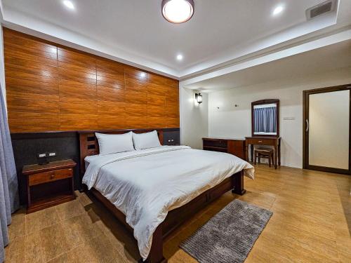 a bedroom with a large bed with a wooden wall at Sanaepatan Home Resort - เสน่ห์ป่าตาล โฮม รีสอร์ต in Ban Buak Khang