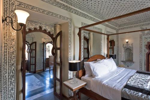 a bedroom with a canopy bed and a mirror at Gogunda Palace in Udaipur