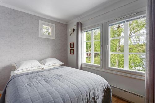 a bedroom with a bed and two windows at Villa Kesätie - Lakeside Paradise in Nurmijärvi