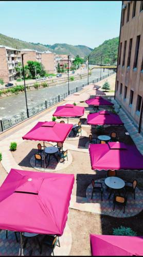 a row of tables with pink umbrellas on a street at Imperial Hotel in Kapan