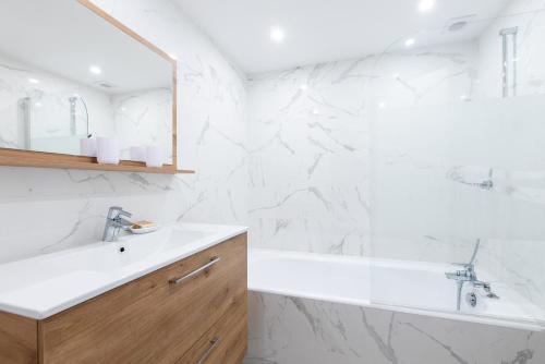 La salle de bains blanche est pourvue d'un lavabo et d'une baignoire. dans l'établissement Lou Amourié - Charmante maison avec terrasse, à Mougins