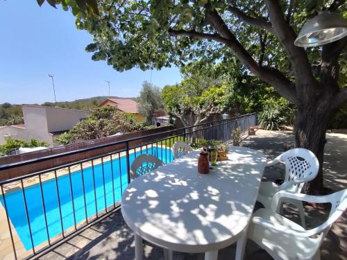 una mesa y sillas en un balcón con piscina en Casa Flor de Taronger, en Viladecans