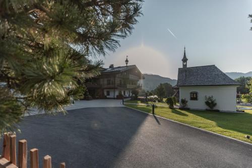 a house with a driveway and a church at Biohof Ebengut in Maria Alm am Steinernen Meer
