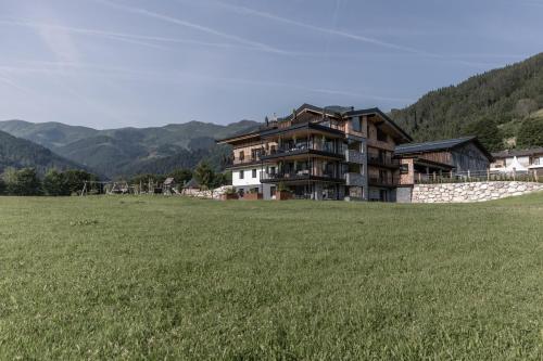 a large house on a hill with a green field at Biohof Ebengut in Maria Alm am Steinernen Meer