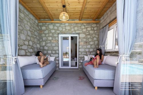 two women sitting on couches in a room at OLIVES seaside villas villa no 2 in Plaka