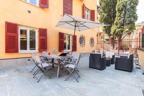 a table and chairs with an umbrella on a patio at Borea Flexyrent apt. AC, parking, close to beach in Rapallo