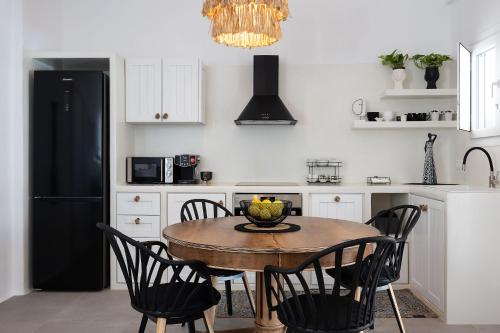 a kitchen with a table and chairs and a black refrigerator at OLIVES seaside villas villa no 2 in Plaka
