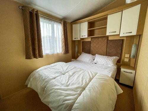 a bedroom with a large bed with white sheets at Lovely Caravan By The Beach In Pakefield, Suffolk Ref 68007cl in Lowestoft