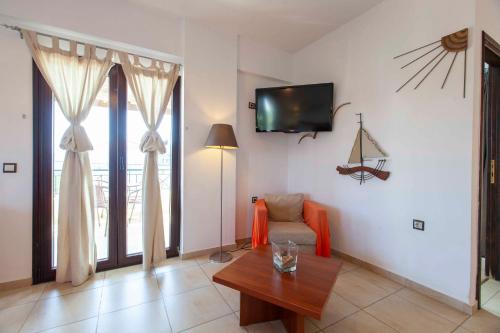 ein Wohnzimmer mit einem Sofa und einem TV an der Wand in der Unterkunft Berdoussis Hotel in Elafonisos