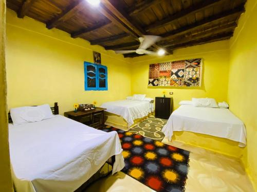 2 Betten in einem Zimmer mit gelben Wänden in der Unterkunft خزفستا Khazfista in ‘Izbat an Nāmūs