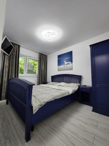 a bedroom with a blue bed and two windows at EDWARD RESIDENCE in Slănic-Moldova