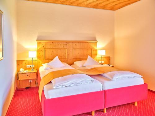 a bedroom with a large bed with a wooden headboard at Parkhotel Bad Griesbach in Bad Griesbach