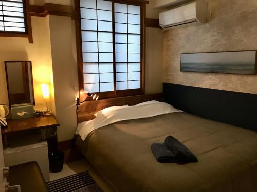 Un dormitorio con una cama con un par de zapatos. en DJANGO Hostel & Lounge, en Tanabe