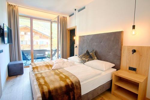 a bedroom with a large bed and a large window at Genusshotel Diamant in Naturno