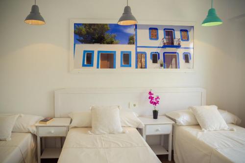 Habitación con 2 camas blancas y una pintura en la pared. en Hostal Sunset Ibiza, en San Antonio
