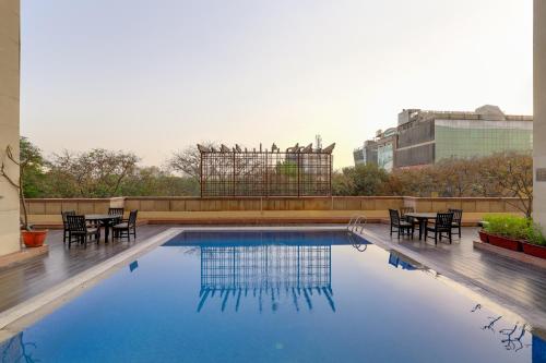 una piscina con mesas y sillas en un edificio en Lemon Tree Premier 1, Gurugram, en Gurgaon