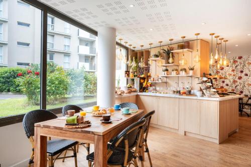 een keuken en eetkamer met een tafel en stoelen bij Séjours & Affaires Paris-Malakoff in Malakoff