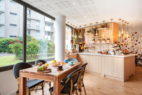 a kitchen and dining room with a table and chairs at Séjours & Affaires Paris-Malakoff in Malakoff