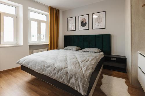 a bedroom with a large bed and two windows at Apartment FRIENDs Bratislava in Bratislava