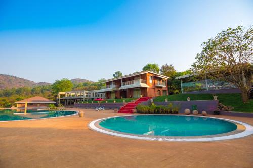 ein Resort mit einem Pool vor einem Gebäude in der Unterkunft Urmilaa Green County Resort 35 KM From Kolhapur in Kolhapur