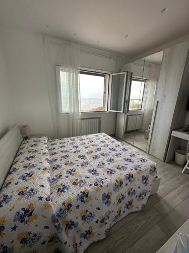 een slaapkamer met een bed met een bloemdekbed bij Camere private vista Faraglioni - Aci Trezza in Aci Castello