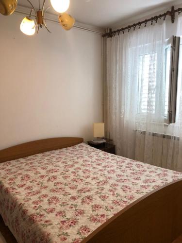Un dormitorio con una cama con una manta de flores y una ventana en Apartman Štefanija, en Novi Vinodolski