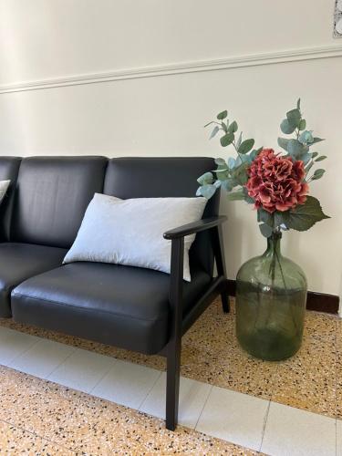 a black couch and a vase with a flower in it at Maison Paulette - charme et authenticité in Bizanet
