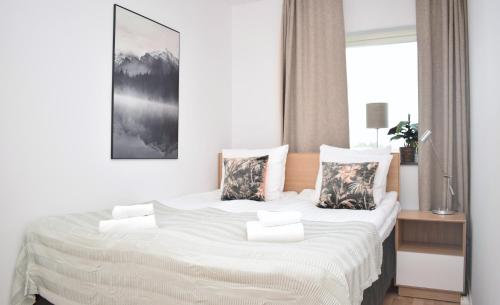 um quarto com uma cama grande com lençóis brancos e almofadas em Apartments Lund em Lund