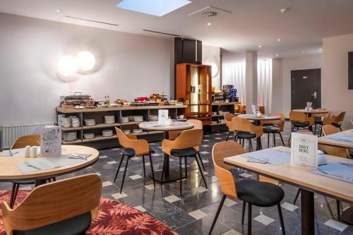 a restaurant with tables and chairs and a kitchen at Hotel H12**** in Kraków