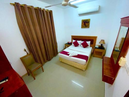 a small bedroom with a bed and a chair at Savoy Inn Hotel Apartments in Muscat