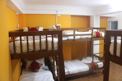 three bunk beds in a room with yellow walls at Nepalaya Home Hostel in Kathmandu