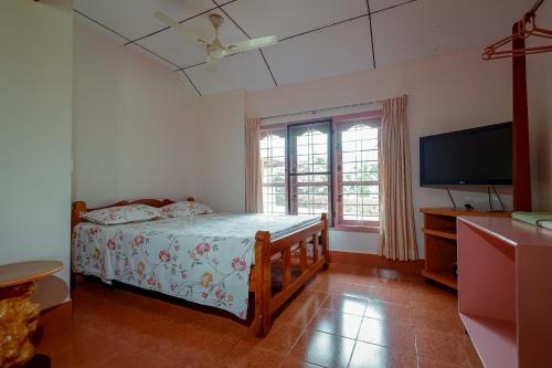 a bedroom with a bed and a flat screen tv at Prakruthi Home Stay in Sollebail