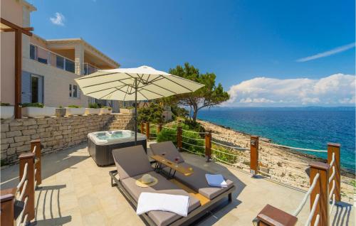 a patio with chairs and an umbrella and the ocean at Awesome Home In Crnja Luka With Kitchen in Prigradica