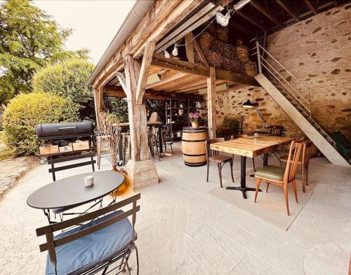 a patio with tables and chairs and a grill at La Cour Verte : Chaleureuse grange réhabilitée in Montépilloy