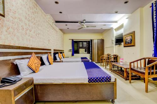 een slaapkamer met een bed en 2 stoelen bij Flagship Hotel Swagat Palace in New Delhi