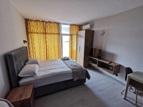 1 dormitorio con 1 cama, TV y ventana en Privately owned Studios Bora Bora, en Nesebar