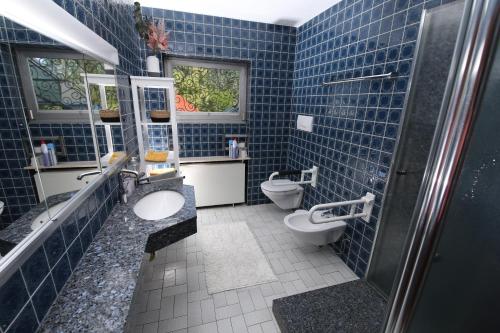 uma casa de banho em azulejos azuis com 2 WC e um chuveiro em Moderne, herzliche und große Ferienwohnung mitten im Naturpark em Grebenhain
