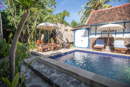 una piscina con sillas y sombrillas junto a una casa en Ardi Beltza Hotel and Private Pool Villa, en Gili Air