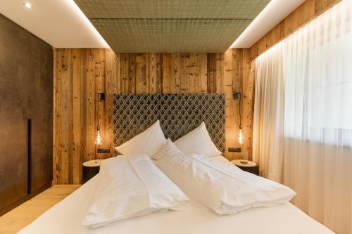 a bedroom with a white bed with wooden walls at Hotel Garni Jagdhof in Zell am Ziller
