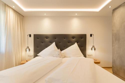 a large white bed with white pillows on it at Hotel Garni Jagdhof in Zell am Ziller