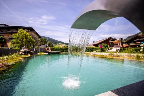 une fontaine au milieu d'un bassin d'eau dans l'établissement Landhaus Rustika, à Wagrain