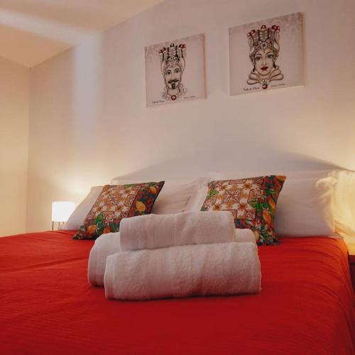 una cama roja con un montón de almohadas en La Rosa dei venti en Calatafimi